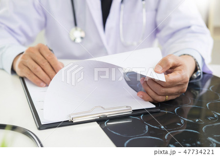 The doctor performs working writing on paperwork and analysis of The doctor performs working writing on paperwork and analysis of 47734221