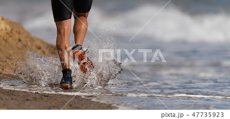 Athlete runner running on waves of sea beach 47735923