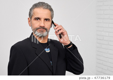 Serious man looking at camera, holding phone. Serious man looking at camera, holding phone. 47736179