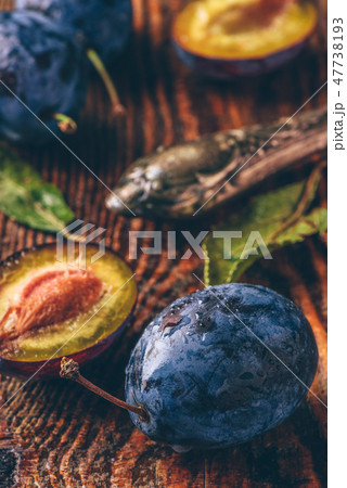 Ripe plums with leaves, water drops and knife Ripe plums with leaves, water drops and knife 47738193