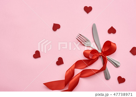 Romantic dinner. Table place setting with red ribbon and decorative hearts Romantic dinner. Table place setting with red ribbon and decorative hearts 47738971