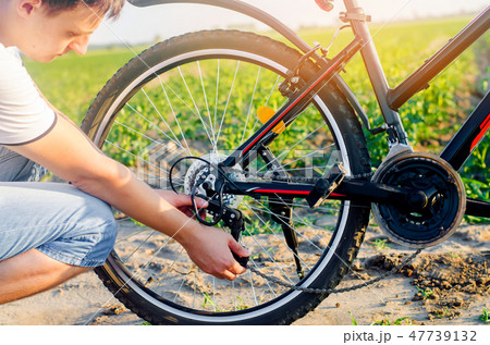 the guy repairs the bicycle. chain repair. cyclist the guy repairs the bicycle. chain repair. cyclist 47739132