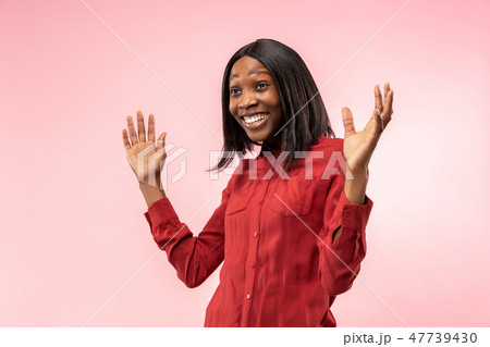 The happy african woman standing and smiling against red background. 47739430