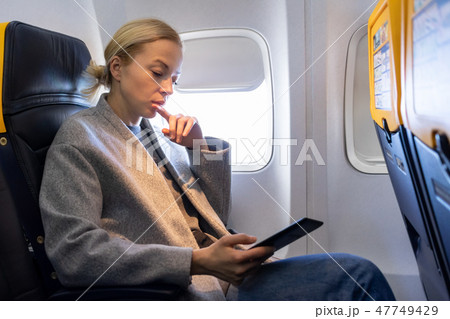 Woman reading on digital e-reader while traveling by airplane. 47749429