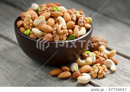 Wooden bowl with mixed nuts on a wooden gray Wooden bowl with mixed nuts on a wooden gray 47750047