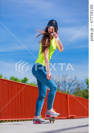 Teen girl skater riding skateboard on street. 47758186