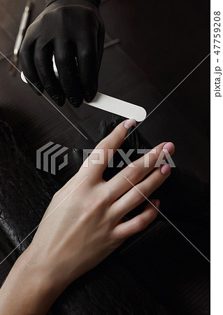 Manicurist in black gloves nail file handles nails Manicurist in black gloves nail file handles nails 47759208