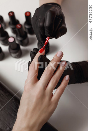Manicurist in black gloves, causes the client Manicurist in black gloves, causes the client 47759250