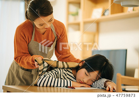 勉強に疲れ居眠りする子供に毛布をかける母親 47759873