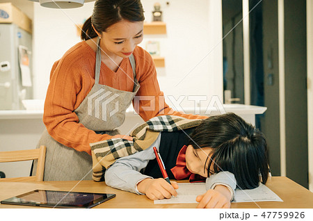勉強に疲れ居眠りする子供に毛布をかける母親 47759926