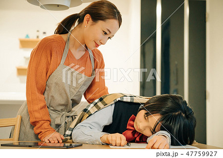 勉強に疲れてうたた寝する子供に毛布をかける母親の写真素材