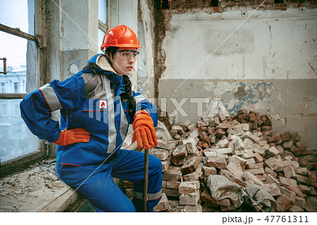 Woman wearing helmet using male work tools Woman wearing helmet using male work tools 47761311