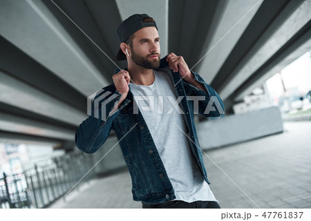 Outdoors leisure. Young stylish man walking on city street wearing wireless earphones listening to Outdoors leisure. Young stylish man walking on city street wearing wireless earphones listening to 47761837