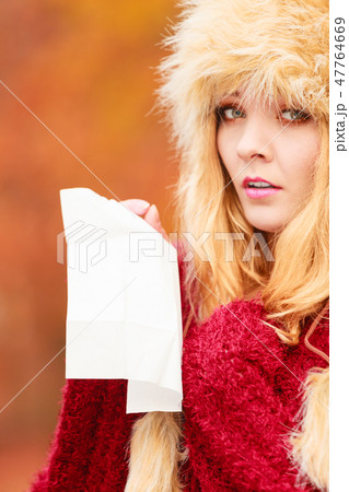 Sick woman in autumn park sneezing into tissue. Sick woman in autumn park sneezing into tissue. 47764669