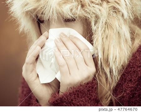 sick woman sneezing in tissue outdoor 47764670