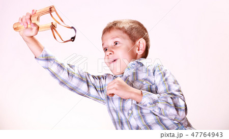 Young boy use sling shot shoot mandarine. 47764943