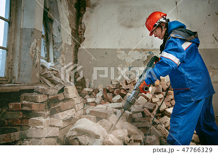 Woman wearing helmet using male work tools Woman wearing helmet using male work tools 47766329