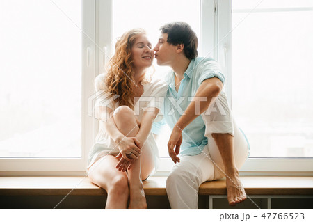 Happy girl and man kissing near window in home. Happy girl and man kissing near window in home. 47766523
