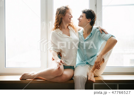 Happy girl and man hugging near window in home. Happy girl and man hugging near window in home. 47766527