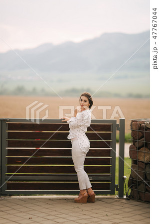 Attractive young girl stand outside in the village, Background of mountains. Bright photo. White 47767044