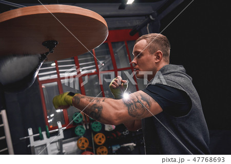 Stay strong to win. Side view of professional young boxer with green hands bandages hitting punching 47768693