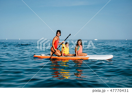 Mother with two daughters stand up on a paddle board 47770431