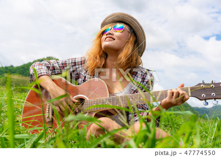 Happy woman plays guitar with nature background. Happy woman plays guitar with nature background. 47774550