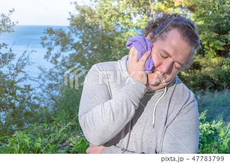 Fat man wipes his face with a towel 47783799