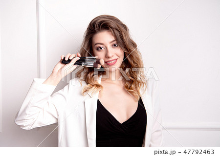 Beautiful young girl with brown hair in her hands holding a professional makeup brush 47792463