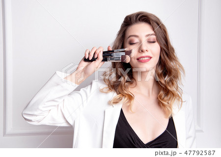 Cute brunette make-up artist using makeup brush. 47792587