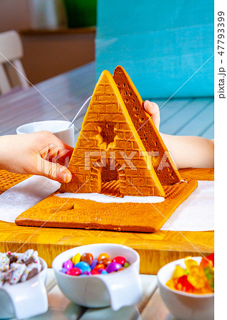 Familiy building a sweet ginger bread house Familiy building a sweet ginger bread house 47793399