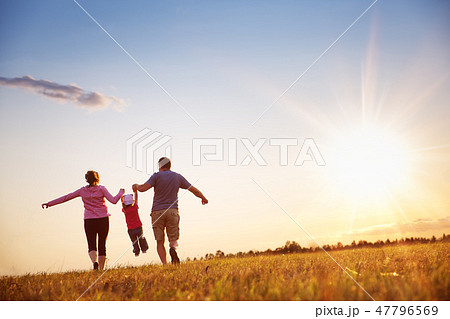 girl with mother and father holding hands on the nature 47796569