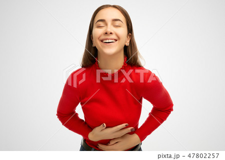 Positive and joyful girl keeps both hands on belly Positive and joyful girl keeps both hands on belly 47802257