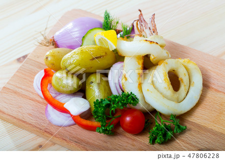 Wooden board with grilled squid rings Wooden board with grilled squid rings 47806228