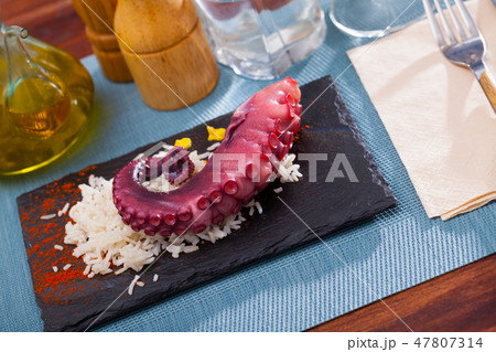 Delicious cooked octopus tentacles on a chopping board Delicious cooked octopus tentacles on a chopping board 47807314