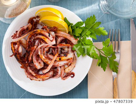 Delicious cooked squid or octopus tentacles with lemon and parsley on a plate Delicious cooked squid or octopus tentacles with lemon and parsley on a plate 47807339