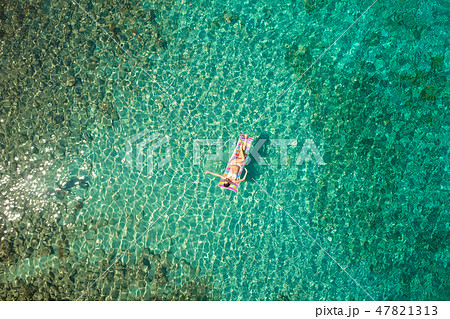 Top down view of a beautiful woman in a white bikini who is floa Top down view of a beautiful woman in a white bikini who is floa 47821313