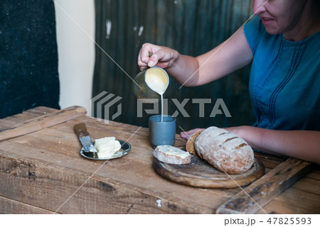 Woman has breakfast adds milk to coffee 47825593