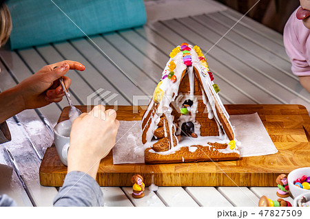 Familiy building a sweet ginger bread house Familiy building a sweet ginger bread house 47827509