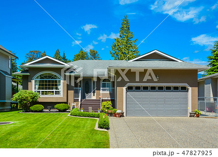Suburban family house with nice lawn, wide garage door, and concrete driveway 47827925