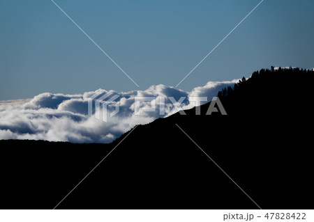 Clouds behind dark mountain peaks, high contrast Clouds behind dark mountain peaks, high contrast 47828422