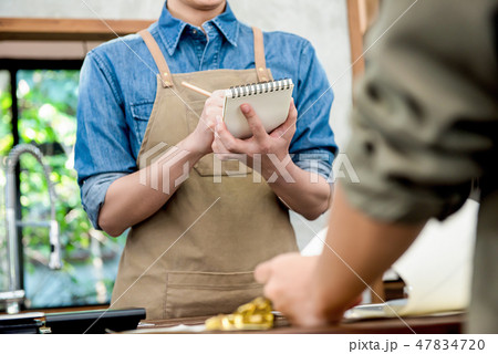 Waiter taking order from customer at the counter 47834720