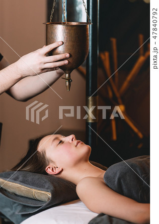 Specialist making shirodhara massage of ayurveda 47840792
