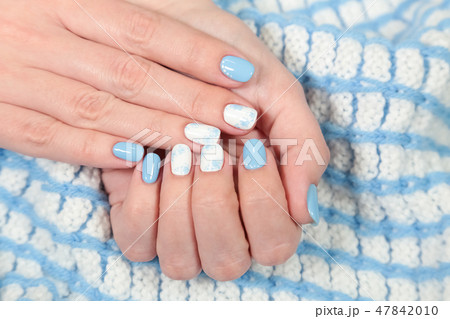 female fingers with painted blue and white nails 47842010