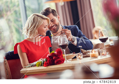Young couple on date in restaurant sitting man feeding woman with salad playful Young couple on date in restaurant sitting man feeding woman with salad playful 47842819