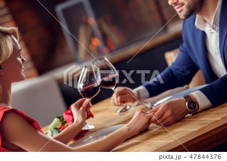 Young couple on date in restaurant sitting drinking wine cheers holding hands Young couple on date in restaurant sitting drinking wine cheers holding hands 47844376