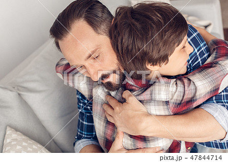 Father and little son at home sitting on sofa hugging happy close-up Father and little son at home sitting on sofa hugging happy close-up 47844714