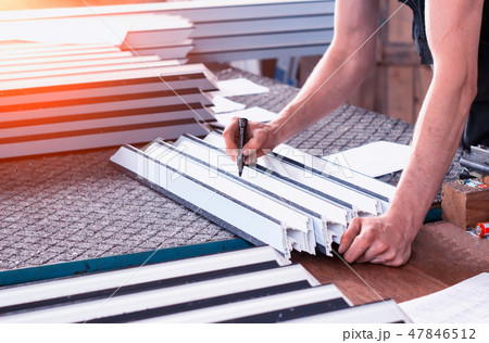 Production of PVC windows, the worker records dimensions on the profile of the frame pvc, felt pen Production of PVC windows, the worker records dimensions on the profile of the frame pvc, felt pen 47846512