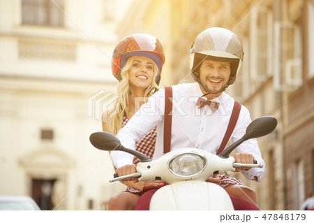 Hipster couple riding a scooter on a sunny day Hipster couple riding a scooter on a sunny day 47848179
