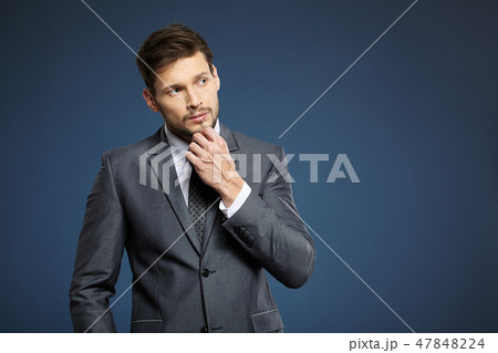 Handsome young business man standing on blue background Handsome young business man standing on blue background 47848224
